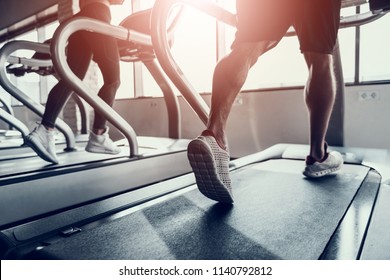 Close up. Man and Young Woman on Treadmills in Gym. Man with Athletic Body. Healthy Lifestyle and Sport Concepts. Young Woman in Training Club. Active Indoor Training. Sport Equipment. - Powered by Shutterstock