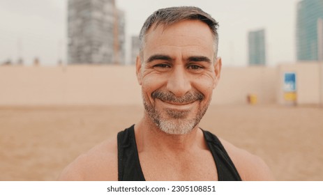 Close up, middle aged athletic man smiling and looking at camera while standing on the beach - Shutterstock ID 2305108851