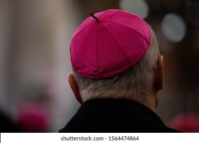 close -up of one cleric in the amaranth zucchetto (form-fitting ecclesiastical skullcap) praying during the mass in the chapel