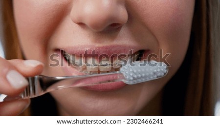 Close Up. Oral hygiene for braces. Teen girl cleaning and brushing teeth with clear ceramic braces using special brushing tools.