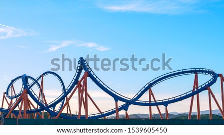CLOSE UP: Panoramic view of an empty rollercoaster ride with sharp turns and twists on a sunny summer evening in LA, California. Cool view of a breathtaking funfair ride on the Santa Monica Pier.