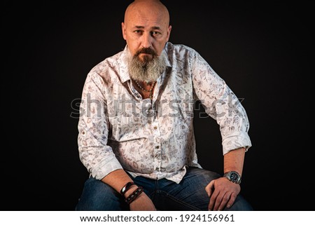 close up, portrait of emotional, thoughtful, handsome positive young bearded businessman man sitting on chair. Low key isolated on dark background. Body language