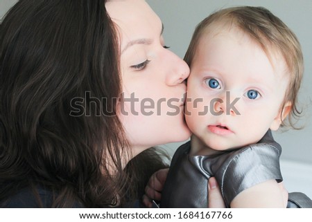 Close up, Portrait of teenage girl hugging and kissing her charming 1 Years Old Baby Sister with Big Blue Eyes. Concept of a warm relationship between siblings in a family