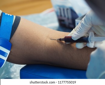 Close up, Puncture of a vein through the skin in order to withdraw blood for analysis.The nurse uses a syringe to venipuncture the patient's arm.