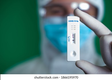 Close up. Rapid antigen COVID-19 test. Quick rapid diagnostic test with positive results. Doctor in protective suit and medical mask hold antigen test. Green screen.