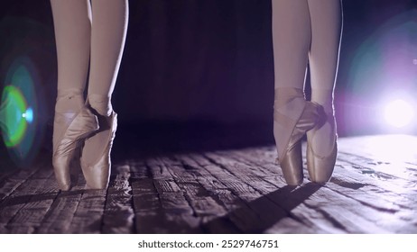 close up, in rays of spotlight, on the stage of the old theater hall. ballerinas standing on toes in pointe shoes, performs elegantly a certain ballet exercise, pas de bourre suivi