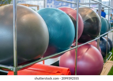 Close up: row of fitness exercise balls, rolled red yoga mats - sport accessories at gym - nobody, no people. Training, inventory, equipment concept