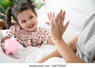 Close Up, Single Mother And Daughter Hi Five Hand A Cute Little Girl, Delighted To Finish Saving Money For Her In The Pink Piggy Bank At Home.