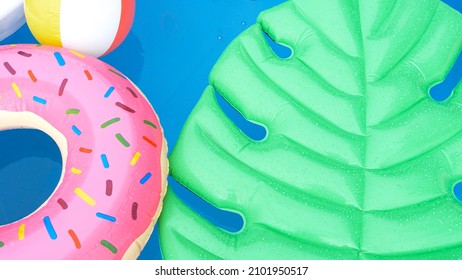 CLOSE UP, TOP DOWN: Raindrops Fall Down On The Colorful Toys Floating Around The Empty Home Pool. Late Summer Rain Falls On The Objects Left In The Pool. Drops Of Rain Create Ripples In The Pool.