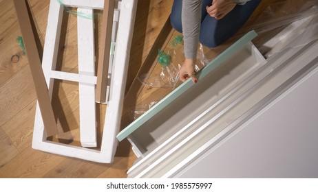 CLOSE UP, TOP DOWN: Unrecognizable Young Woman With Red Nails Finishes Unpacking A Trendy Dresser Drawer In Her Bedroom. Female Moving Into Her New Apartment Unboxes A Modern White Chest Of Drawers.