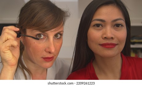 CLOSE UP: Two Beautiful Women Using Beauty Products For Applying Face Make Up. Caucasian And Asian Woman Getting Ready For A Girls Night Out. Attractive Ladies Having Fun While Using Make Up Products.