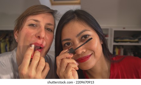 CLOSE UP: Two Ladies Using Make Up Products And Getting Ready For A Girls Night Out. Asian And Caucasian Woman Applying Facial Beauty Products. Cheerful Females Having Fun While Doing Their Make Up.