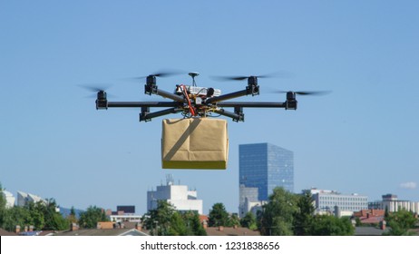 CLOSE UP: UAV drone delivery delivering big brown post package into urban city - Shutterstock ID 1231838656