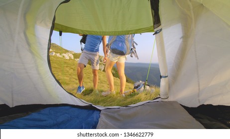 CLOSE UP: Unrecognizable Active Couple Pick Up Their Backpacks And Go On A Hike. Cool Shot From The Inside Of A Tent Of A Young Man And Woman Setting Off On A Hike In The Picturesque Julian Alps