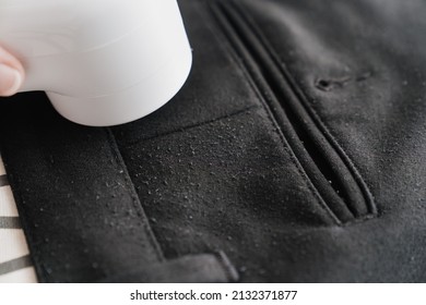 close up. use a machine for removing pellet and spools from clothes and fabric on black trousers. A modern electronic device for updating old things.