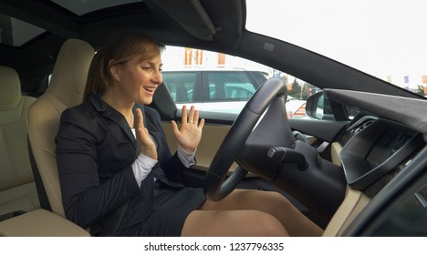 CLOSE UP: Young Businesswoman Is Amazed At The High Tech Car Parking Itself In Reverse Into A Vacant Parking Spot In The Crowded Car Park. Female Driver Lets Self Parking Car Back Up Into Empty Space.