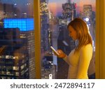 CLOSE UP: Young female tourist texting friends from hotel room above the flashing lights of Times Square. Businesswoman typing a text on a sunny evening while still in her office in downtown New York