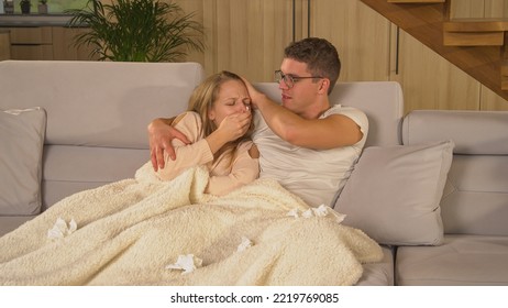 CLOSE UP: Young Man And Woman On Couch Comforting Each Other During Sickness. Twosome On Sick Leave And Resting On Comfy Couch At Home. Young Married Couple Covered With Blanket And Trying To Recover.