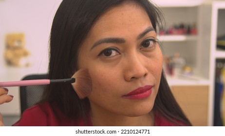 CLOSE UP: Young Philippine Lady Using Brush For Applying Bronzer To Her Face. Mirror Reflection Of Pretty Woman Applying Face Blush To Beautify Her Face. Female Person Taking Care Of Her Fresh Look.