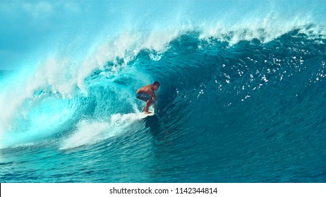 CLOSE UP: Young Pro Surfer Surfs A Big Barrel Wave In Popular Surf Spot In Breathtaking Tahiti. Awesome View Of A Extreme Surfboarder Riding Epic Blue Waves In The Hot Summer Sun Of French Polynesia.