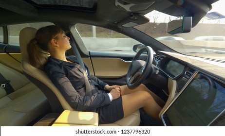 CLOSE UP: Young Well Dressed Woman Napping In An Autonomous Car Driving Her Along The Freeway And Back Home From Work. Businesswoman Resting During Her Commute In An Advanced Self Steering Vehicle.