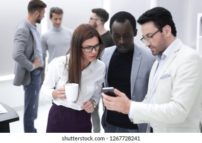 close up.a group of employees reading a message on a smartphone
