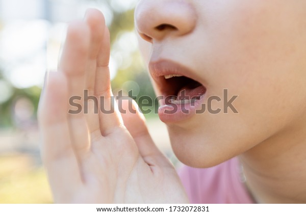 Close up,Asian young woman raised her hand near\
her mouth to whisper or speaks softly and gossip,child girl telling\
a secret or talking in a low voice,sharing a secret,whispering and\
gossiping concept