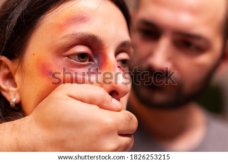 Close upf woman with bruises because of agressive husband. Violent aggressive husband abusing injuring terrified helpless, vulnerable, afraid, beaten and panicked wife.