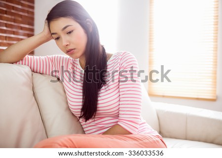 Close up of upset asian woman on couch at home in the living room
