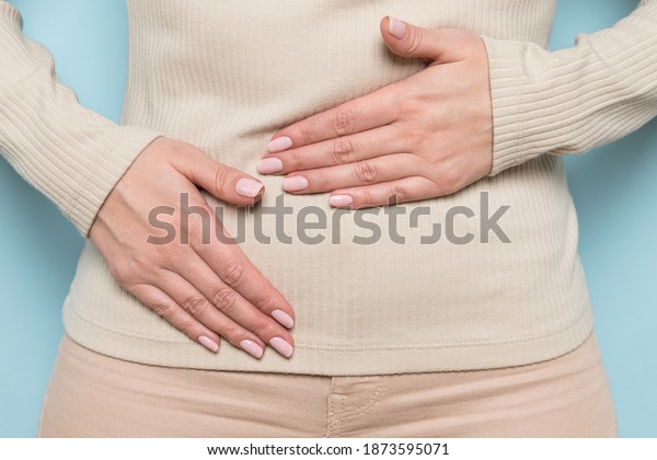 Close up of upset woman hold belly suffer from\
abdomen ache, female feel pain hurt in stomach abdominal gastritis,\
pancreatitis, food poisoning, appendicitis symptom, standing over\
blue wall.