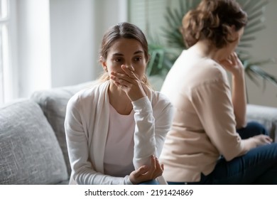 Close up upset young woman and mature mother avoid to talk after quarrel, sitting back to back on couch at home, offended grownup daughter and elderly mum argument, two generations conflict concept