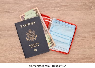 Close Up Of US Passport With Jamaican One Hundred Dollar Paper Currency And Face Mask On Wood Grain Table