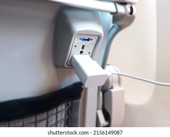 Close up of a USB and 110V power port plug on airplane seat for charging personal electronic batteries while flying. Devices such as phones, tablets, and laptops can be used for work and entertainment