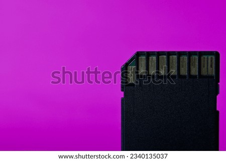 Close up of a used SD card straight on with purple backrop.