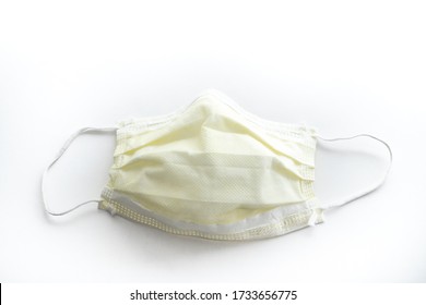 Close Up Of A Used Yellow Doctors Mask Or Nurse Mask Face Covering Looking Straight Down Isolated On A White Background.