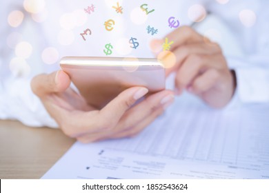 Close Up Using Mobile With Money Symbol Usd, Euro, Gbp, Krw, Cny On Document For Earning From Online Business. Finance And Technology In 2021 Year Concept.