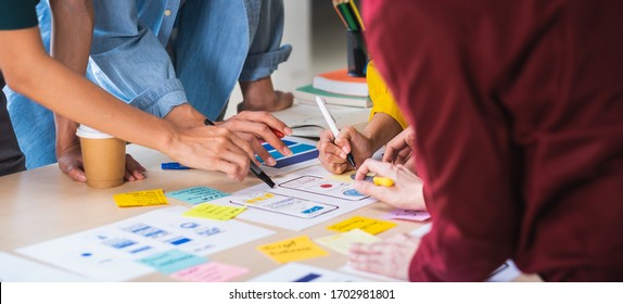 Close up ux developer and ui designer brainstorming about mobile app interface wireframe design on table with customer brief and color code at modern office.Creative digital development agency.panning