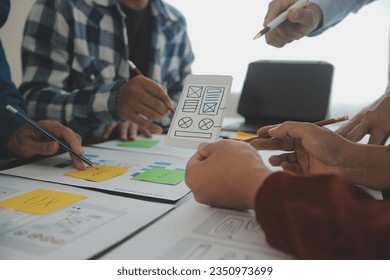 Close up ux developer and ui designer brainstorming about mobile app interface wireframe design on table with customer breif and color code at modern office.Creative digital development agency