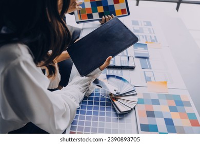 Close up ux developer and ui designer brainstorming about mobile app interface wireframe design on table with customer breif and color code at modern office.Creative digital development agency