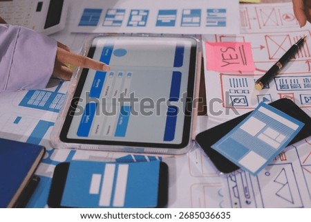 Close up ux developer and ui designer brainstorming about mobile app interface wireframe design on table with customer breif and color code at modern office.Creative digital development agency.