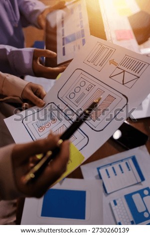 Close up ux developer and ui designer brainstorming about mobile app interface wireframe design on table with customer breif and color code at modern office.Creative digital development agency.