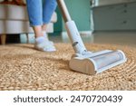 Close up of vacuum cleaner brush cleaning carpet on floor. Woman using portable cordless vacuum cleaner. Daily routine and household chores