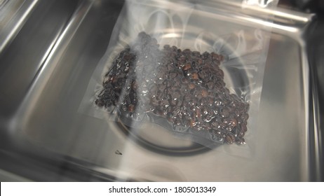 Close up of vacuum packaging of coffee beans process. Extending the shelf life of products concept. Automated sealing machine packing coffee in plastic bag - Powered by Shutterstock