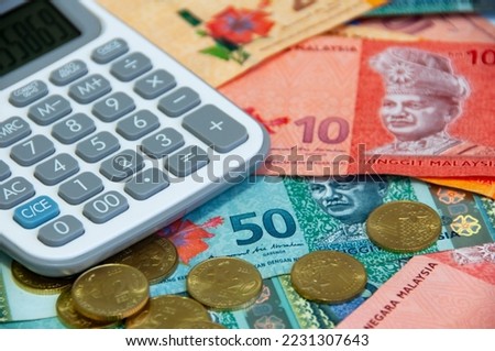 Close up of various Malaysia Ringgit currency and coins with calculator.