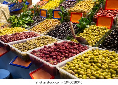 Close Up Of Various Olives Standing In Plastic Container On Deli Counter In Market Place