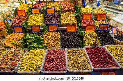 Close Up Of Various Olives Standing In Plastic Container On Deli Counter In Market Place