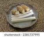 Close up of various pieces of Yeot(Malt Candy) with sesame and peanut on ceramic dish and mat floor, South Korea
