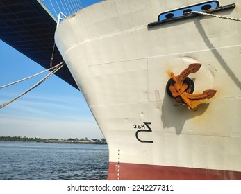 Close up veiw of a large anchor was pulled into place as it moored in the pier, near a high bridge. Big carrier, Bow side, Marine industry area.
