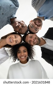 Close up vertical low angle portrait of smiling multiethnic diverse employees pose together look at camera laughing. Happy young multiracial workers friends have fun show unity. Diversity concept.