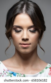 Close Up Vertical Portrait Of Pretty Young Woman Face With Make Up And Perfect Olive Skin Complexion Over Gray Studio Background.